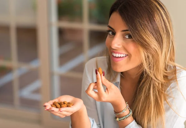 美しい若い女性を笑顔とナッツを家で食べる 健康の概念 — ストック写真