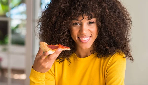 非洲裔美国妇女准备吃辣香肠比萨饼切片与愉快的面孔站立和微笑以自信的微笑显示牙 — 图库照片