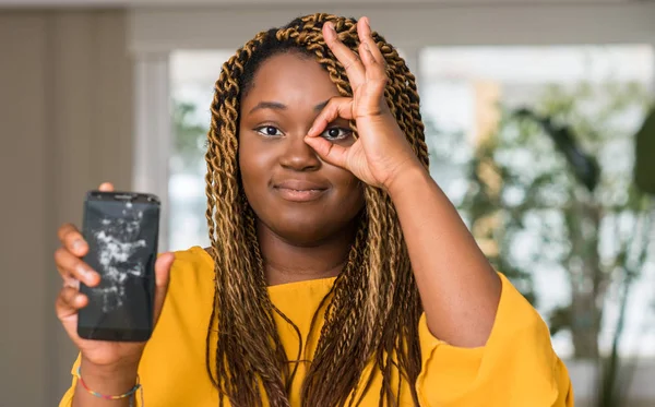 Afrikalı-Amerikalı kadın mutlu yüz el parmaklarının arasından seyir göz üzerinde ok işaretiyle yapıyor gülümseyen ile kırık smartphone gösterilen