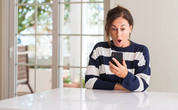 中年女子使用智能手机惊吓休克与惊讶的脸 害怕和激动的恐惧表情 — 图库照片