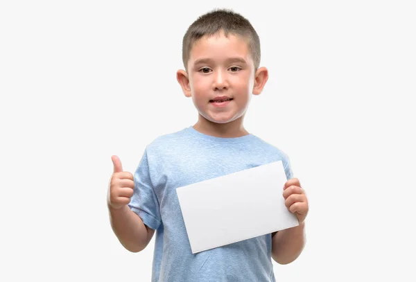 黑发小孩子拿着一张空白卡片开心的笑着做 拇指竖起手指 好兆头 — 图库照片