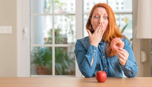 Rossa Donna Sceglie Tra Mela Ciambella Bocca Copertura Con Mano — Foto Stock