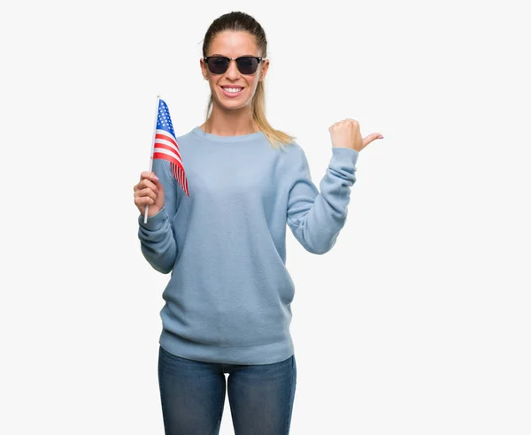 美丽的年轻女子拿着美国国旗指着手和手指与快乐的脸微笑 — 图库照片