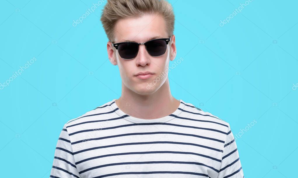 Young handsome blond man wearing sunglasess with a confident expression on smart face thinking serious
