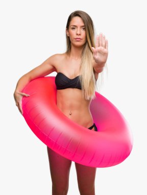 Güzel genç kadın ile pembe float tutan bikini açık dur işareti ile ciddi ve kendine güvenen ifade, savunma hareketi yaparken el
