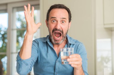 Kocaman bir gülümseme ile çığlık zaferini kutluyor ve ellerini kaldırdı su çok mutlu ve heyecanlı, kazanan ifade bir kadeh içmek orta yaş erkek