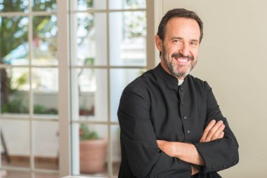Hıristiyan rahip adam ayakta ve diş gösterilen kendine güvenen bir gülümsemeyle gülümseyerek mutlu bir yüz ile