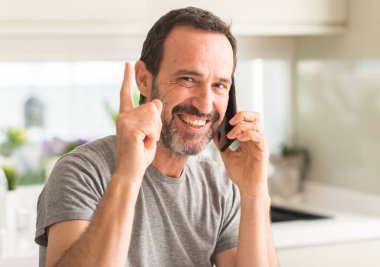 Smartphone sürpriz bir fikirle kullanan yaş adam orta veya gülen yüz, bir numara ile işaret parmağı soru