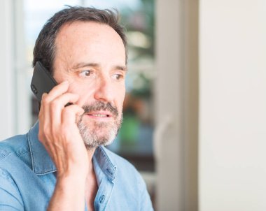 Acımak yüz ciddi düşünüyorum üstünde kendine güvenen bir ifade ile akıllı telefon kullanan orta yaş adam