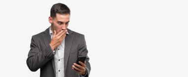 Yakışıklı genç adam için hata, ifade korku, utanç ile şok el ile Smartphone kapak ağzı kullanarak sessizlik içinde gizli kavramı korkuttu