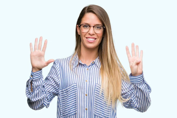 Şık gömlek ve gösterilen ve parmakları ile işaret gözlük güzel genç kadın numara 9 kendinden emin ve mutlu gülümseyerek süre.