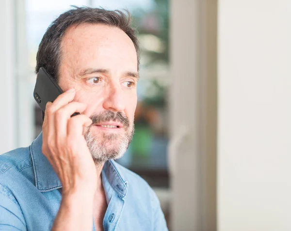 Middle age man using smartphone with a confident expression on smart face thinking serious