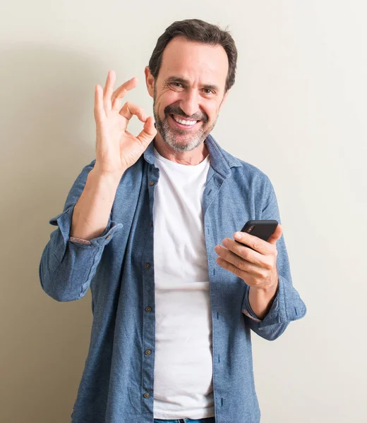 Senior Man Using Smartphone Doing Sign Fingers Excellent Symbol — Stock Photo, Image