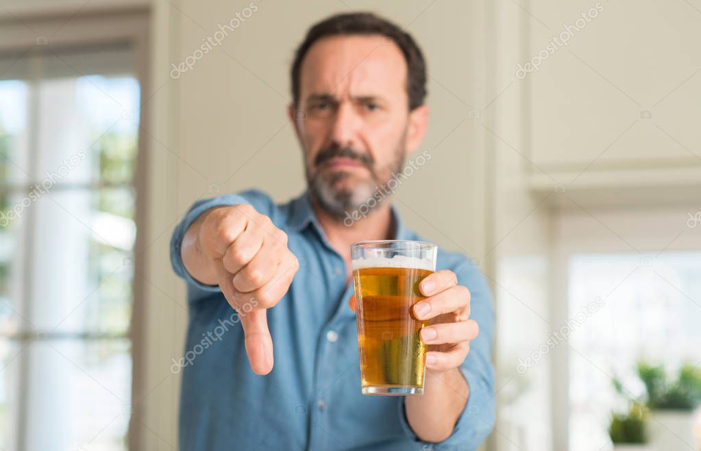 Middle age man drinking beer with angry face, negative sign showing dislike with thumbs down, rejection concept