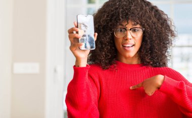 Sürpriz yüz işaret parmağı kırık smartphone için kendini tutan Afrikalı-Amerikalı kadın