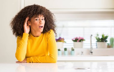 Bir işitme söylenti ya da dedikodu için dinleme kulak üzerinde el ile gülümseyen mutfak at sarı kazak giyen Afrikalı-Amerikalı kadın. Sağırlık kavramı.