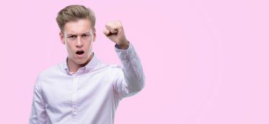 Genç yakışıklı sarışın adam öfkeyle, çılgın ve yükseltilmiş eliyle diye bağıran rahatsız ve hayal kırıklığına uğramış öfke kavramı bağırarak