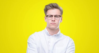 Genç yakışıklı sarışın adam şüpheci ve sinir, onaylamayan ifade yüz çapraz kolları üzerinde. Negatif kişi.