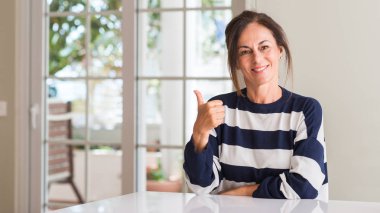 Middle aged woman happy with big smile doing ok sign, thumb up with fingers, excellent sign clipart