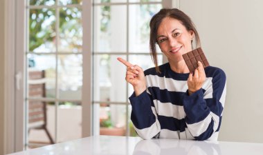 Orta yaşlı kadın çikolata el ve parmak ile tarafına işaret çok mutlu yemek