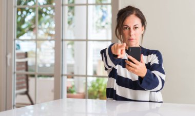 Kamera ve size parmak ile işaret smartphone kullanan kadın orta yaşlı, el işareti, pozitif ve kendinden emin bir jest ön