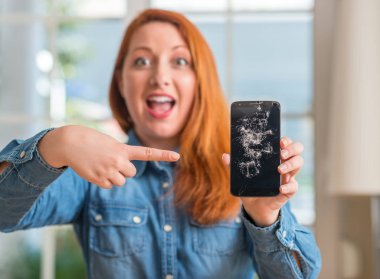 Kırık smartphone çok mutlu el ve parmak ile işaret tutan Kızıl saçlı kadın