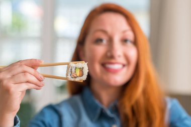 Duygu tezahürat gurur çığlık ve zafer ve başarı çok heyecanlı, kutluyor yemek çubukları kullanarak suşi yemek Kızıl saçlı kadın