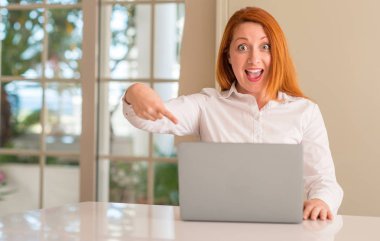 Ev çok mutlu el ve parmak ile işaret bilgisayar dizüstü kullanan Kızıl saçlı kadın