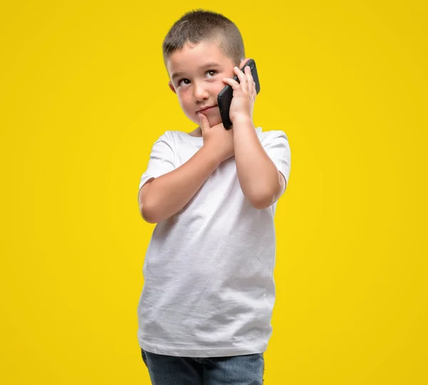 Dunkelhaarige Kleine Kind Mit Einem Smartphone Ernstes Gesicht Über Frage — Stockfoto