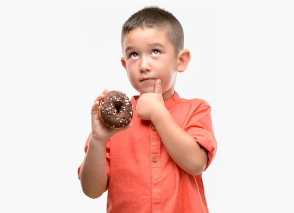 Dark Haired Klein Kind Eten Donut Ernstige Gezicht Denken Vraag — Stockfoto