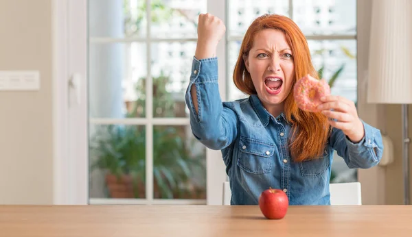 Rödhårig Kvinna Väljer Mellan Apple Och Donut Irriterad Och Frustrerad — Stockfoto