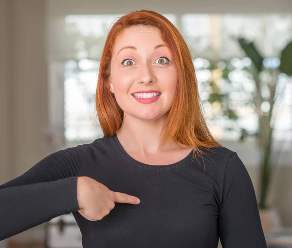 Redhead woman at home with surprise face pointing finger to himself