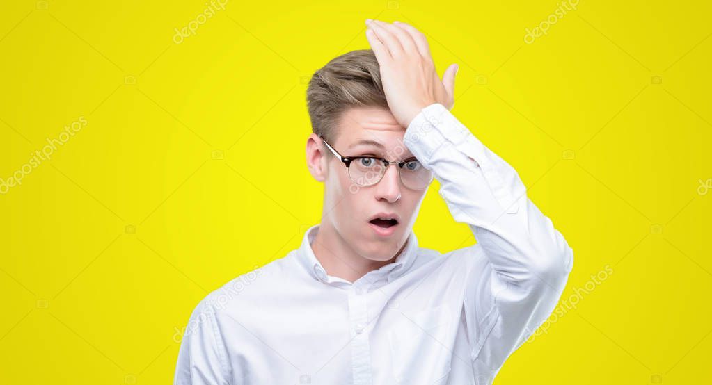Young handsome blond man surprised with hand on head for mistake, remember error. Forgot, bad memory concept.