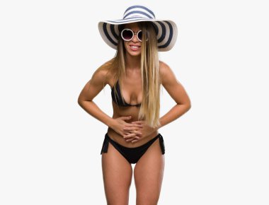 Bikini, güneş gözlüğü ve şapka el ile mide üzerinde çünkü giyen güzel genç kadın hazımsızlık, ağrılı hastalık hasta hissediyor. Ağrısı kavramı.