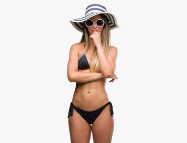 Bikini, güneş gözlüğü ve emin çapraz kollar ve çeneme kaldırdı el ile gülümseme ile kamera seyir şapka giyen güzel genç kadın. Pozitif düşünce.