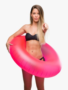 Pembe float kamera ve size parmak ile işaret tutan bikinili güzel genç kadın, el işareti, pozitif ve kendinden emin bir jest ön