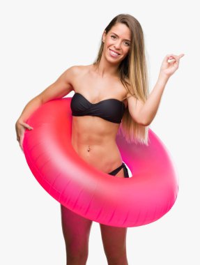 Güzel ve genç birbayan pembe tutan bikini float çok mutlu el ve parmak ile işaret yan