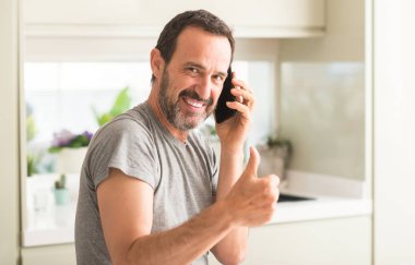 Ok işareti, başparmak ile parmak, mükemmel işareti yapıyor kocaman bir gülümseme ile Smartphone mutlu kullanan orta yaş adam