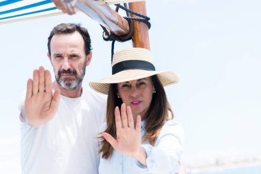 Orta yaş çift Yelkenli ile seyahat eden Dur işareti ile ciddi ve kendine güvenen ifade, savunma hareketi yaparken el açmak