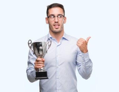 El ve parmak ile yukarı dönük mutlu yüz gülümseyen ile kupayı tutarak yakışıklı genç