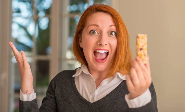 Redhead Woman Eating Cereal Bar Home Very Happy Excited Winner — Stock Photo, Image