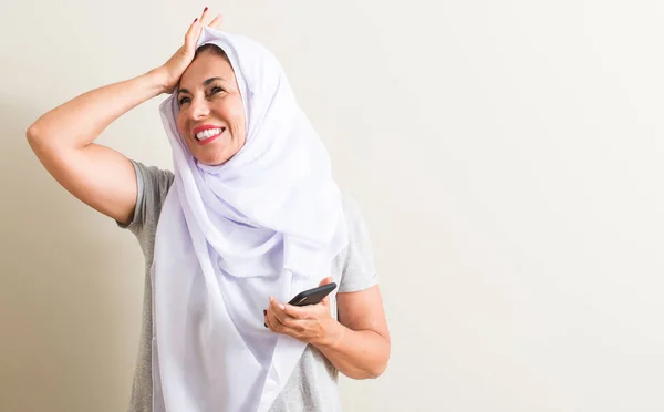 恥と驚きの顔で衝撃を与えたアラビアの女性の頭の上の手を強調したスマート フォンを使用して怒っているとイライラします 恐怖と動揺の間違い — ストック写真