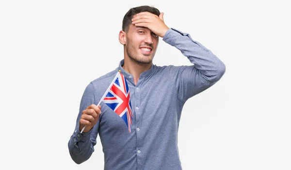 英俊的年轻人拿着英国国旗 手放在头上 感到羞愧和惊讶的脸 愤怒和沮丧 对错误的恐惧和不安 — 图库照片