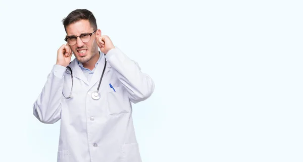 ハンサムな若い医者人の騒々しい音楽のノイズの腹が立つ式の指を使って耳をカバーします 聴覚障害者の概念 — ストック写真