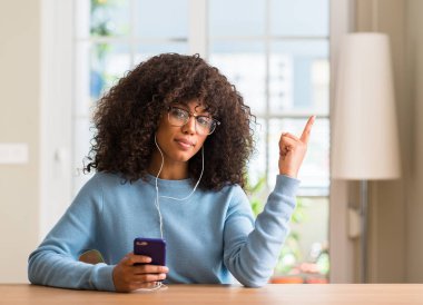 El ve parmak ile tarafına işaret çok mutlu Smartphone kullanarak güzel bir Afrikalı-Amerikalı kadın