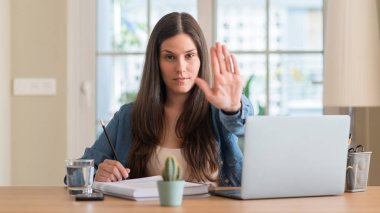 Genç öğrenci kadın açık eliyle dur işareti ile ciddi ve kendine güvenen ifade, savunma jest yapıyor evde eğitim