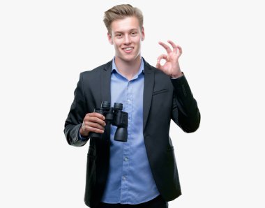 Genç yakışıklı sarışın adam parmak, mükemmel sembolü ile ok işareti yapıyor dürbün üzerinden seyir