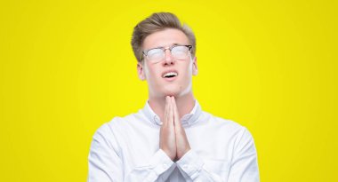 Yalvarıyor ve umut ifade yüzünde çok duygusal ve endişe ile birlikte elleriyle dua genç yakışıklı sarışın adam. Bağışlanmak. Din kavramı.