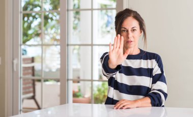 Orta yaşlı kadın açık eliyle dur işareti ile ciddi ve kendine güvenen ifade, savunma hareketi yapıyor