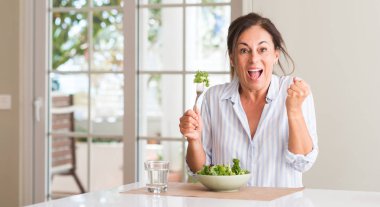 Duygu tezahürat bir kaseye gurur çığlık ev ve kutluyor zafer ve başarı çok heyecanlı, taze salata yemek orta yaşlı kadın